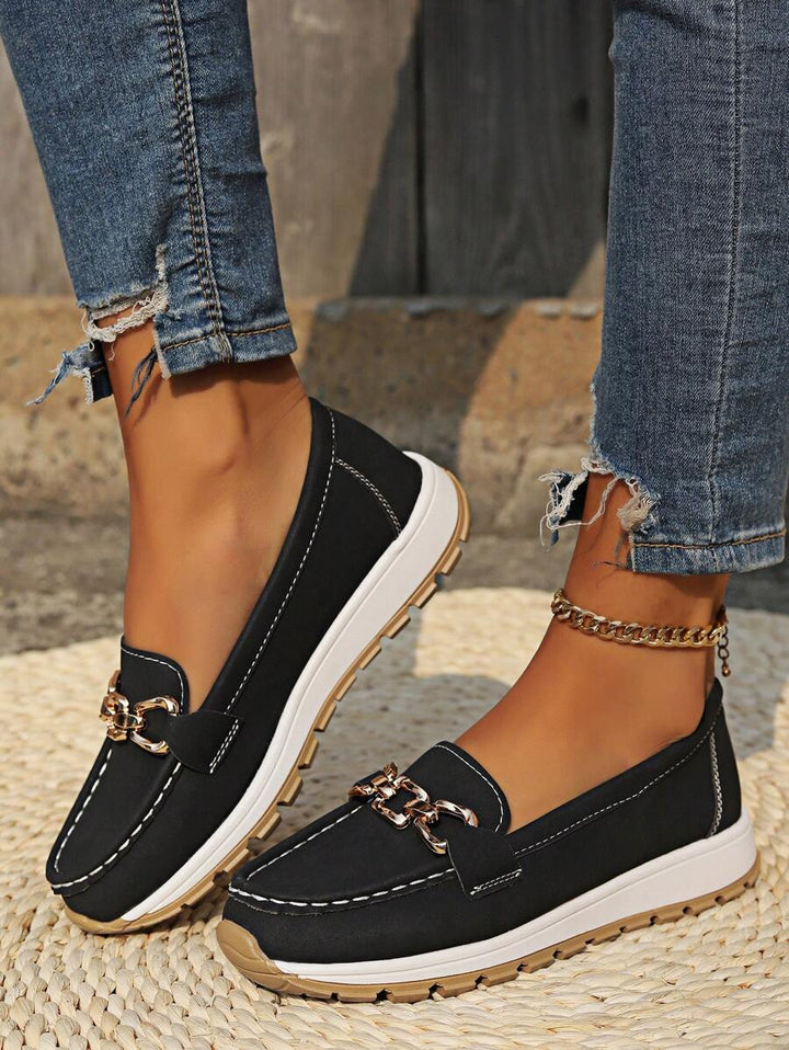 Detail of the elevated flatform sole and gold chain trim on women's stylish slip-on loafers, comfortable footwear.
