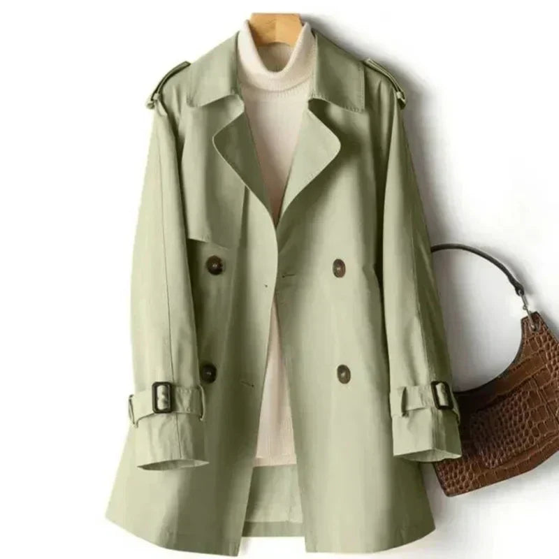Full-length view of a women's elegant double-breasted trench coat, featuring a waist belt & adjustable cuffs.