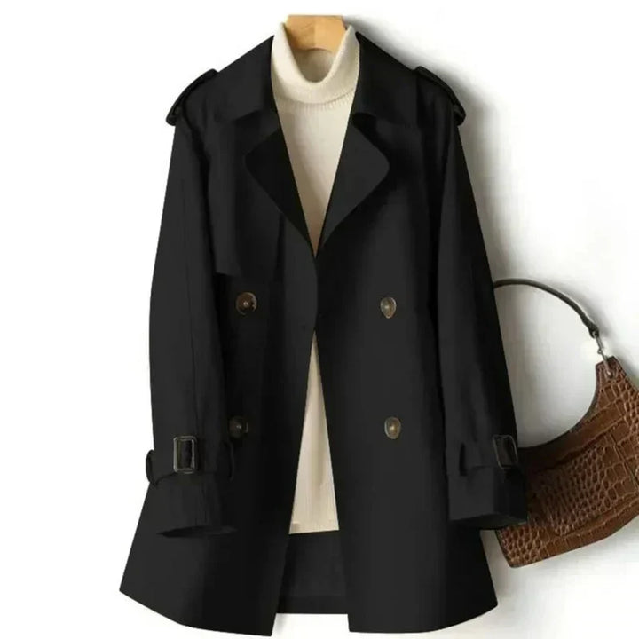 Detail of a women's double-breasted trench coat: belted waist, adjustable cuffs, & classic design.