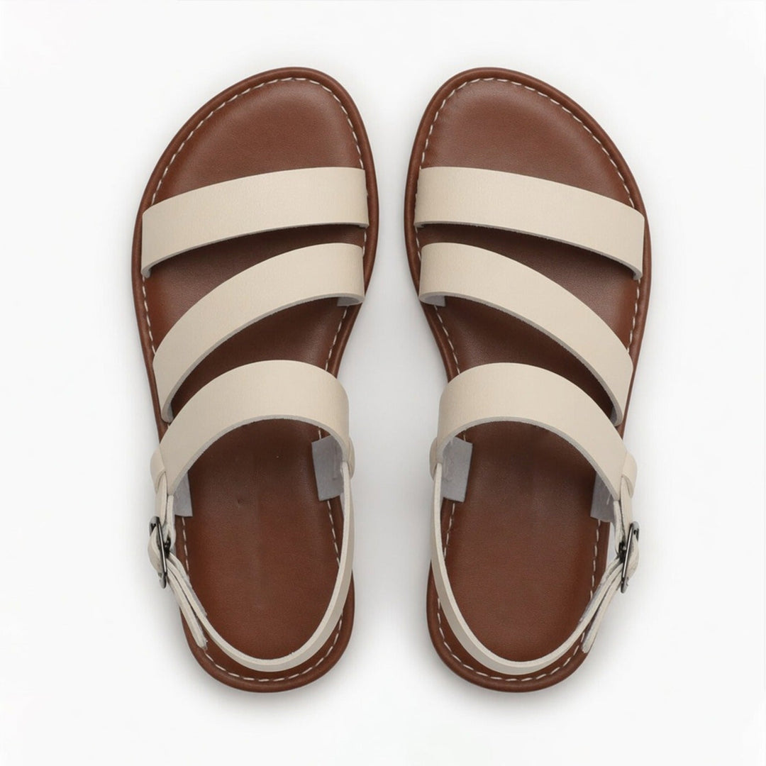 Elegant women's flat sandals with distinctive crossover strap & open toe, ideal for summer style.