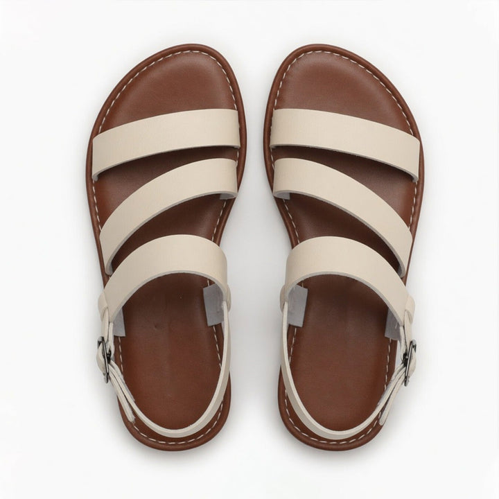 Elegant women's flat sandals with distinctive crossover strap & open toe, ideal for summer style.