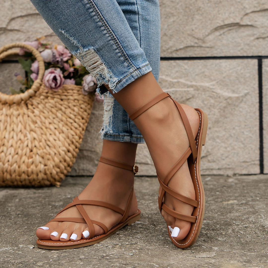 Trendy women's open-toe flat sandals with crossover toe loop and ankle strap for stylish summer comfort.