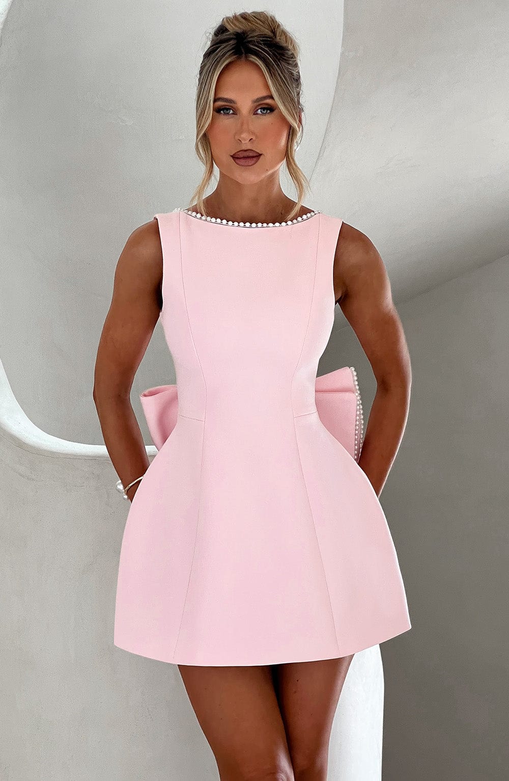 Women's elegant A-line mini homecoming dress with delicate pearl trim and bow detail. Perfect for special occasions.