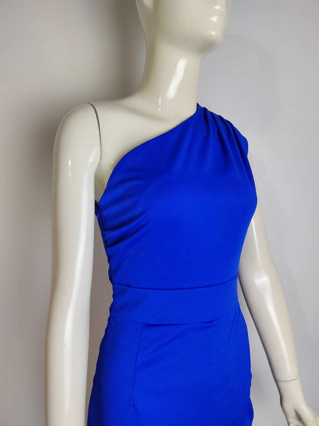 Side view of women's sophisticated evening gown, showcasing asymmetrical drape and leg slit.