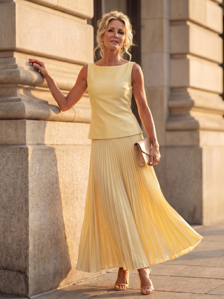 Women's elegant black two-piece set with structured sleeveless top & flowing pleated maxi skirt.