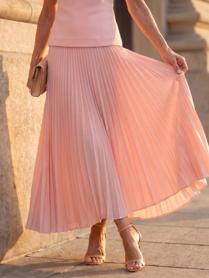 Women's elegant pink two-piece set for evening, featuring a structured bodice & a long pleated skirt.