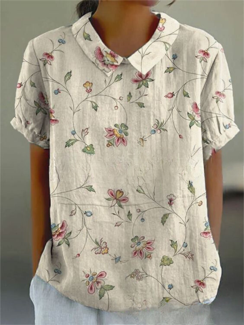 Close-up of feminine women's blouse with delicate floral embroidery & classic Peter Pan collar.