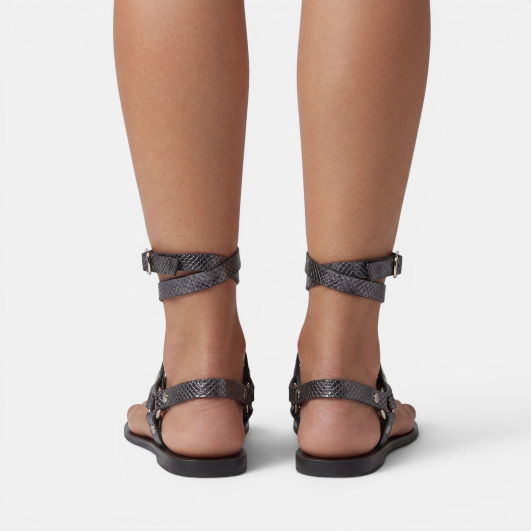 Women's buckled snake print flat sandals. Trendy crossover strap design provides comfortable & stylish summer footwear.