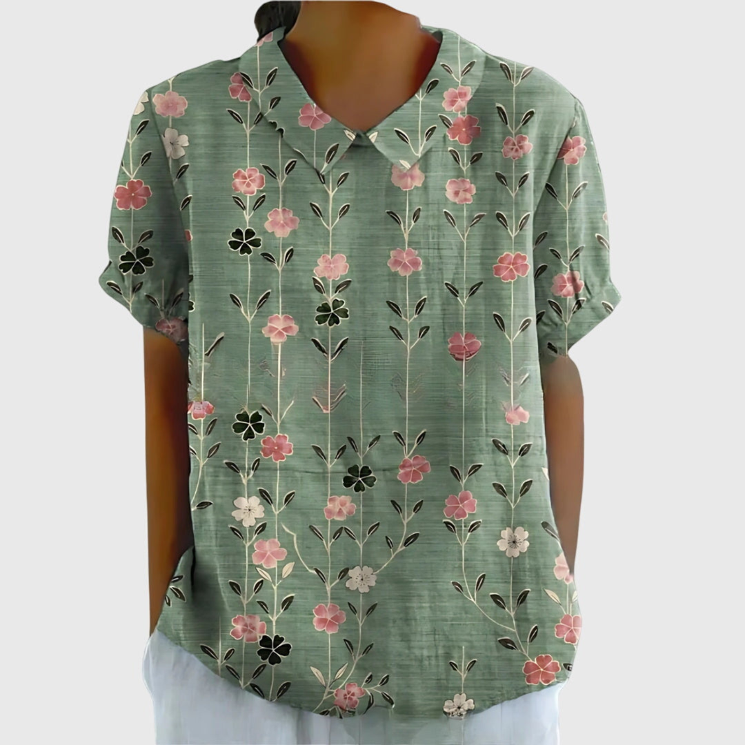 Close-up detail of the vibrant floral print on a women's collared short sleeve blouse. Summer fashion.