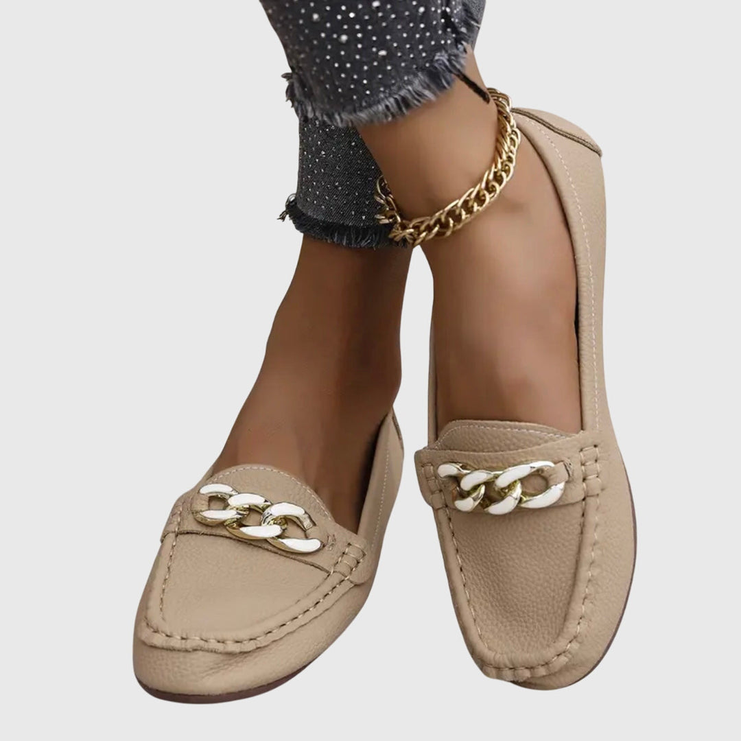 Close-up of women's gold-chain wedge loafers, showing crystal detail.