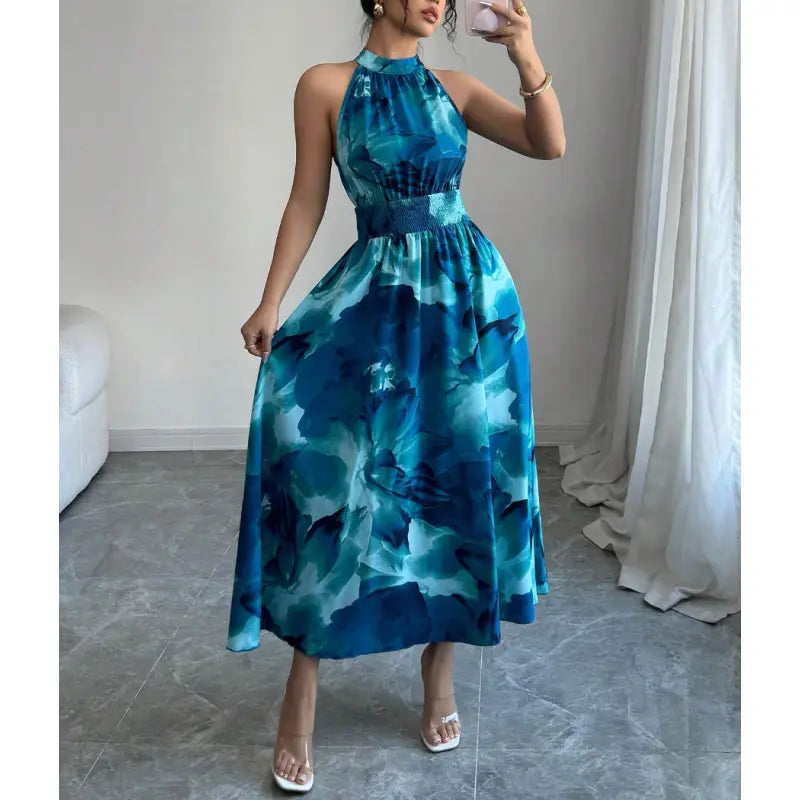 Elegant women's sleeveless halter neck maxi dress featuring an abstract pattern & smocked waist, ideal for vacation.