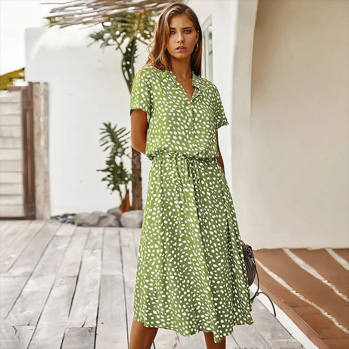Woman models a chic leopard print short-sleeve midi dress. Features button-down front & self-tie belt.
