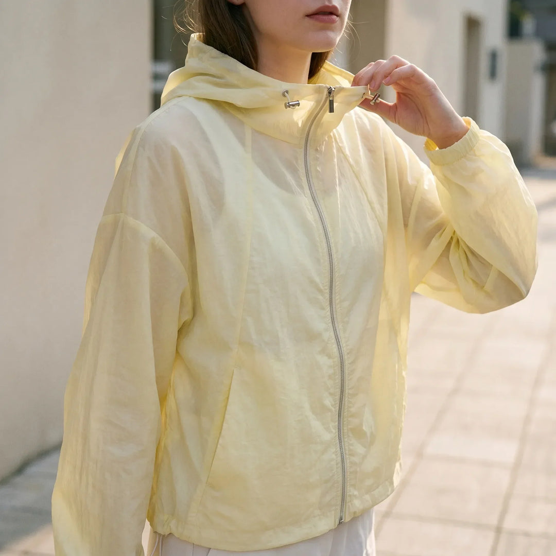 Women's lightweight hooded windbreaker jacket with full zip, pockets, and elastic cuffs for activewear.