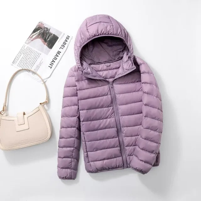 Women's packable puffer jacket with hood, folded compactly for travel-friendly storage.