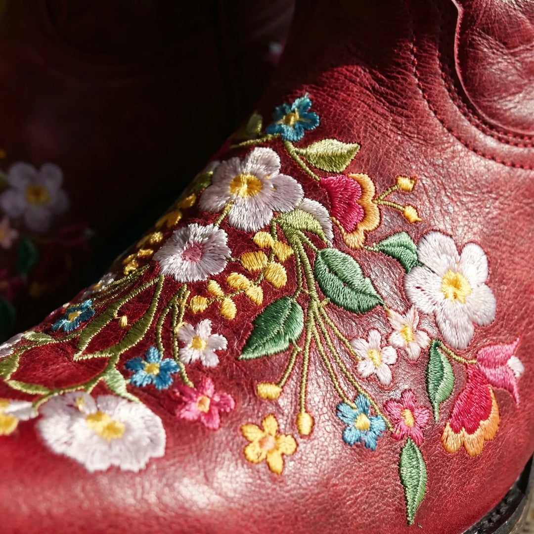 Unique women's cowboy ankle boots with vibrant floral embroidery & pull-on design for a statement look.