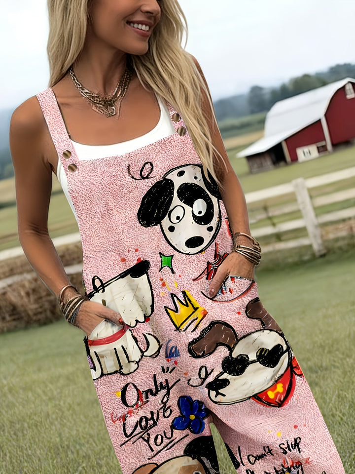 Woman sitting, wearing playful dog print wide-leg jumpsuit with adjustable straps. Casual style.