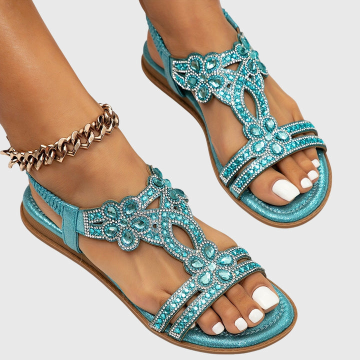 Stylish slip-on flat sandals with intricate rhinestone detail.