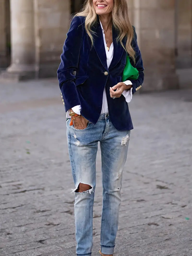 Detailed shot of a women's velvet blazer featuring gold buttons on the front closure.