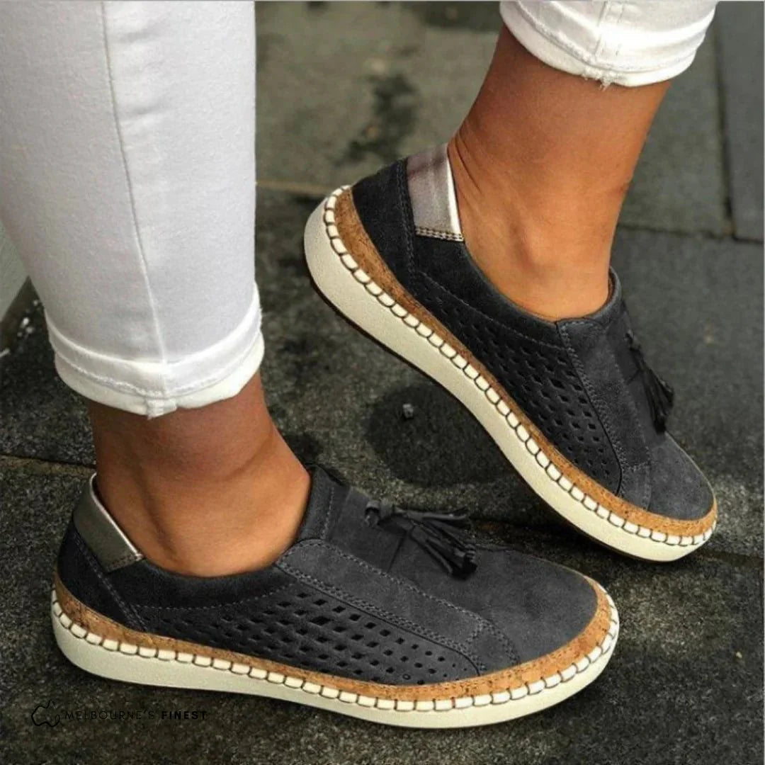 Fashionable women's slip-on perforated sneakers, offering breathability & comfort with stylish tassel details.