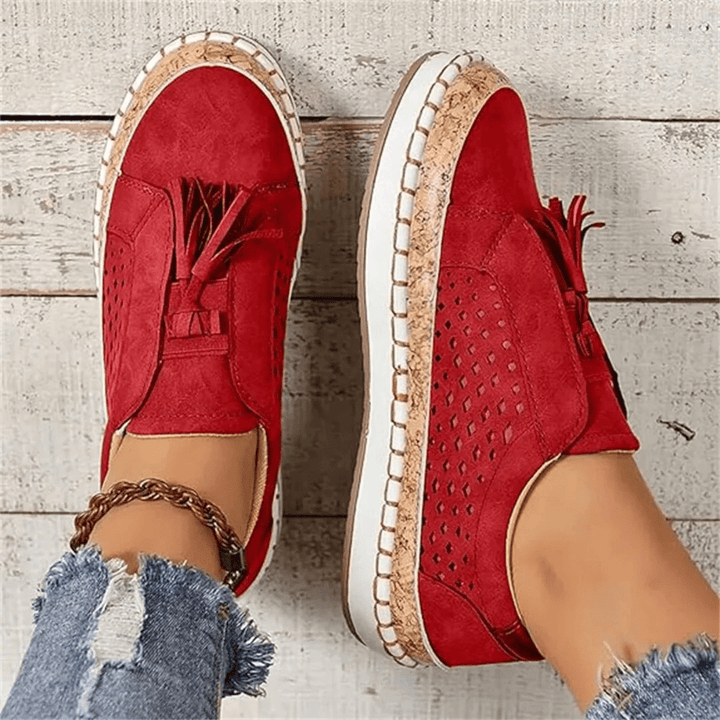 Front view of women's slip-on perforated sneakers, showcasing breathability and stylish tassel embellishments.