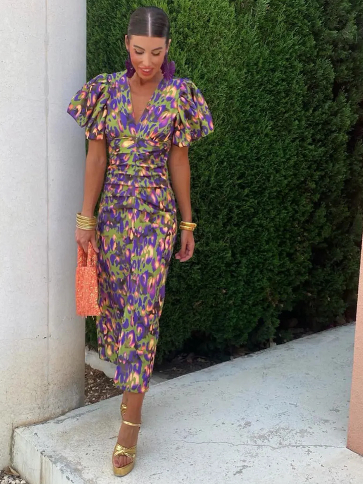 A vibrant women's ruched midi dress in an abstract print, designed for elegant statement style at special events.