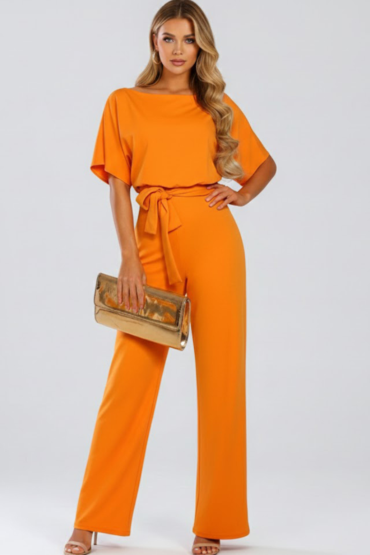 Woman walking in a flowy wide leg short sleeve jumpsuit with belt. Ideal for comfortable, elegant summer fashion.