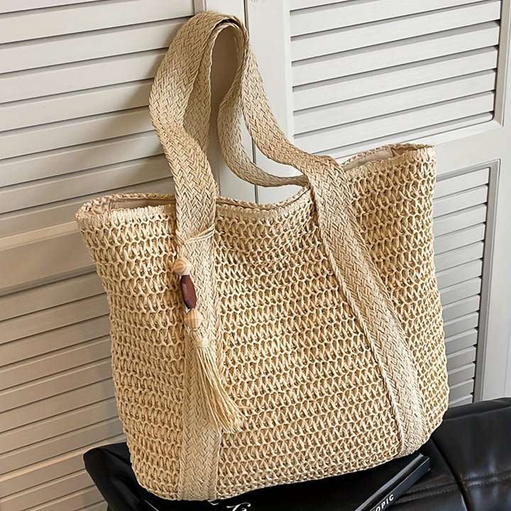 Green woven straw tote bag for women, designed with a chic fringe tassel, perfect for beach days.
