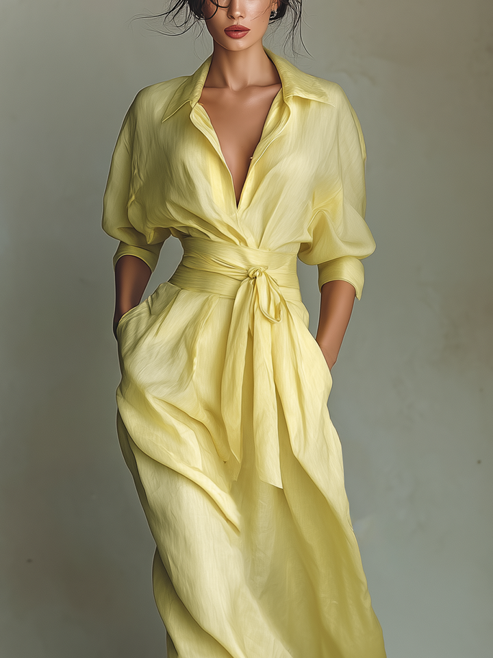 Elegant long yellow women's shirt dress with v-neck, billowy sleeves, and flattering tie waist.