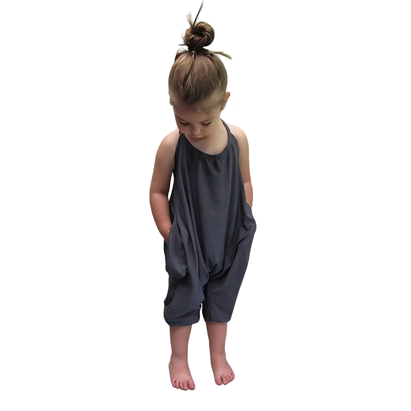 Smiling girl running on grass in a stylish backless harem jumpsuit, summer kids outfit
